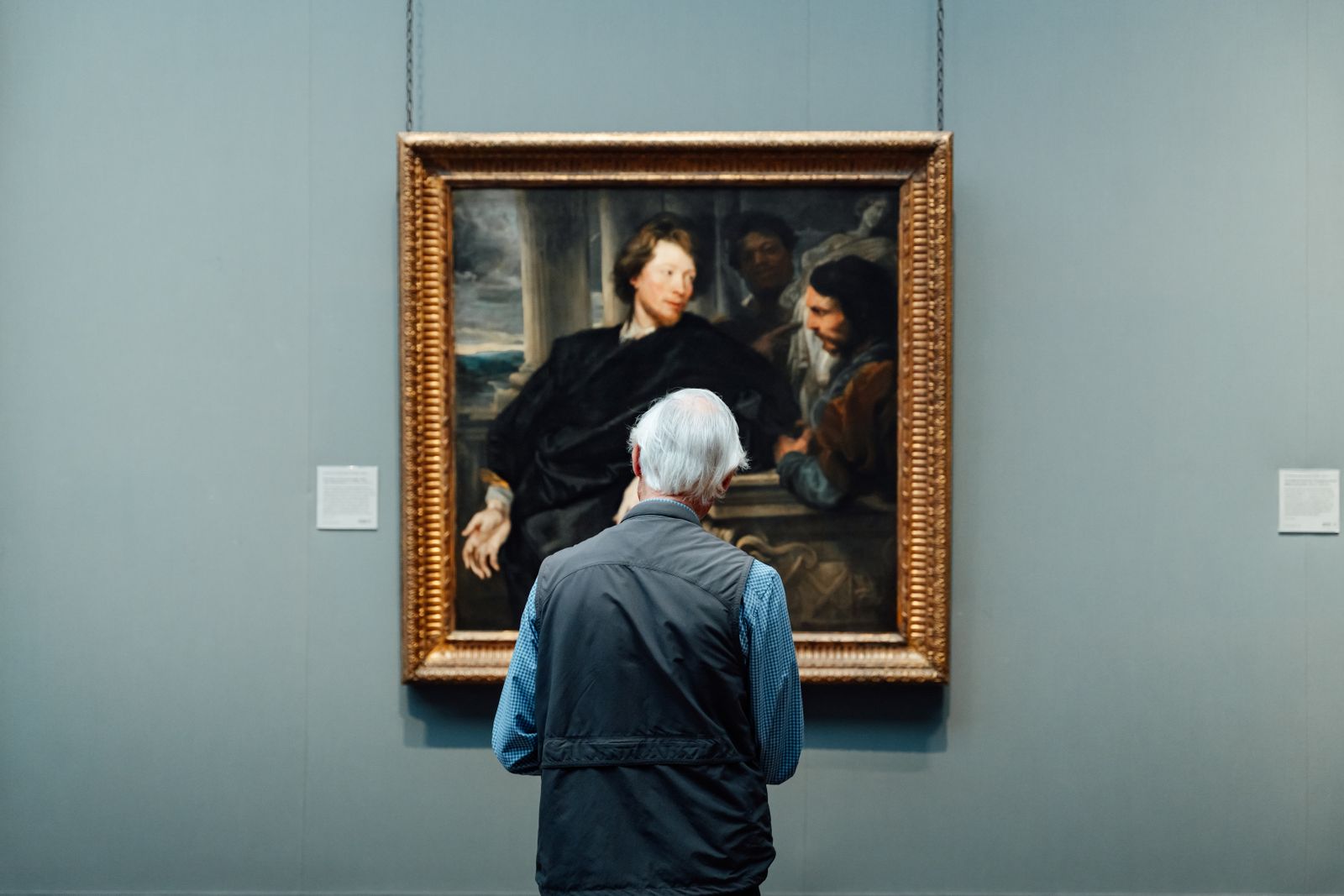 Senior admiring a classic painting in an English art gallery. Engrossed in art appreciation.