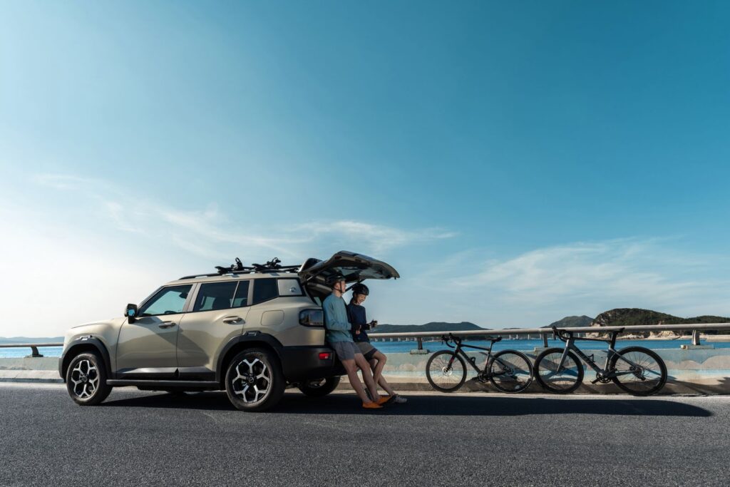 Modern SUV parked on a coastal road with bicycles, ideal for a scenic adventure.