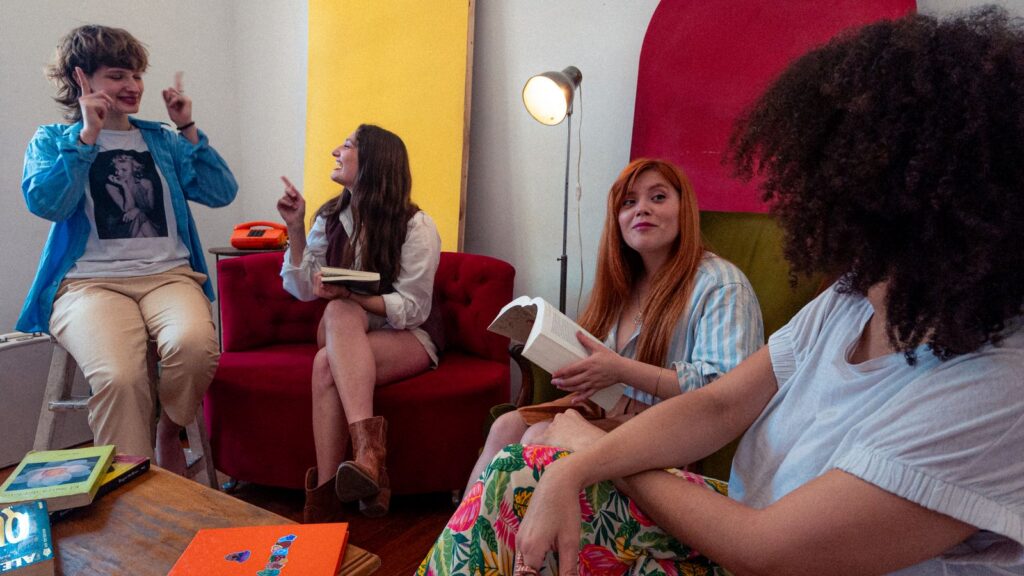 A group of friends enjoy a lively conversation in a bright, vintage-inspired room.