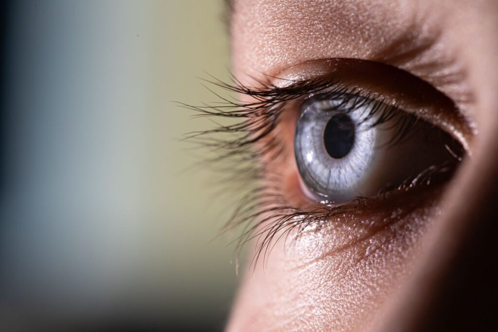 Macro shot of a blue eye highlighting intricate details of the eye and eyelashes.