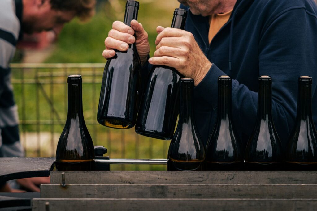 Hands filling wine bottles in an outdoor setting in Nouvelle-Aquitaine, France.