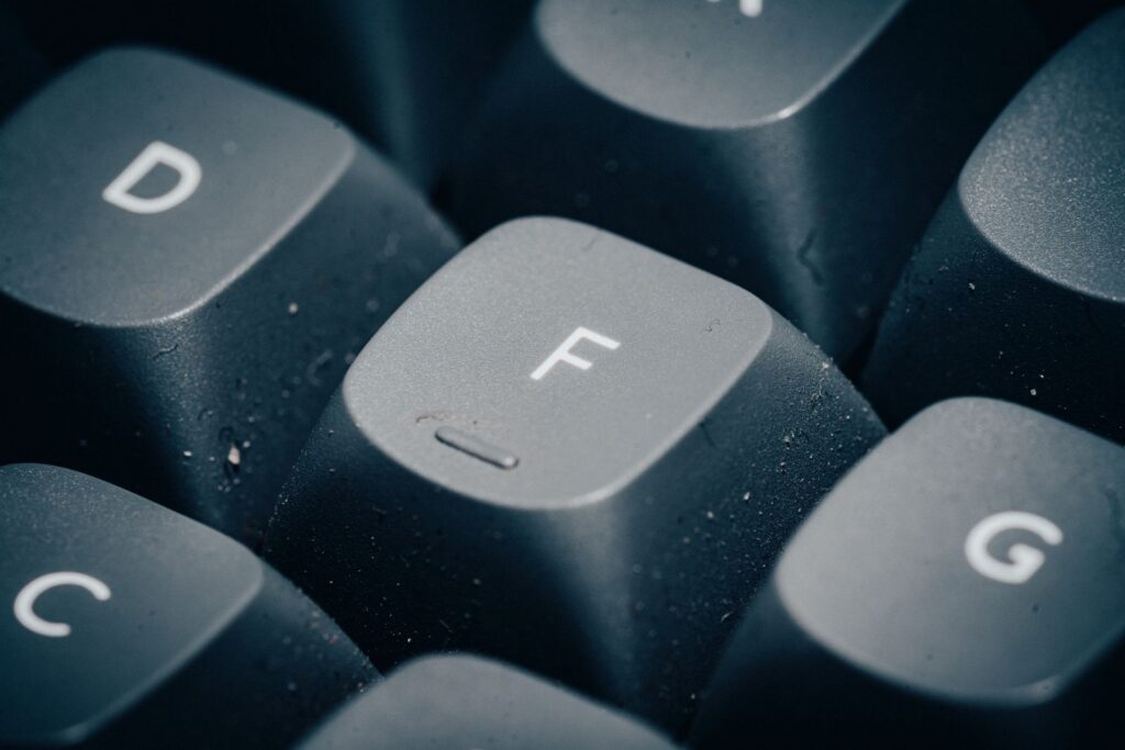 Detailed close-up of dusty keyboard keys with focus on the letter F.