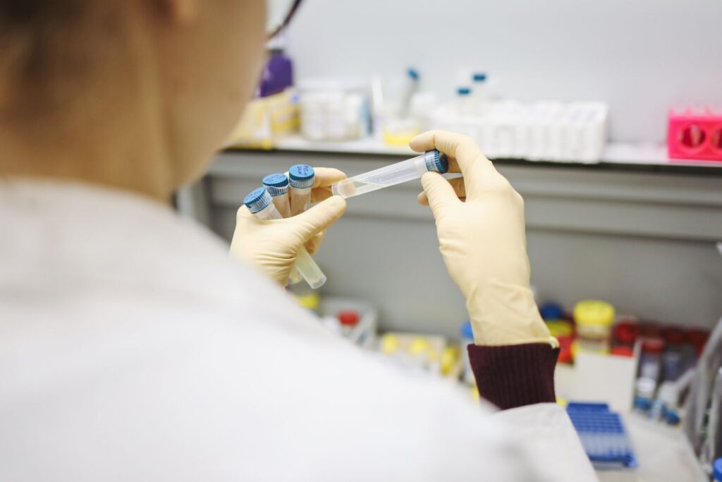 Scientist examining test tubes in a laboratory setting, wearing protective gloves.