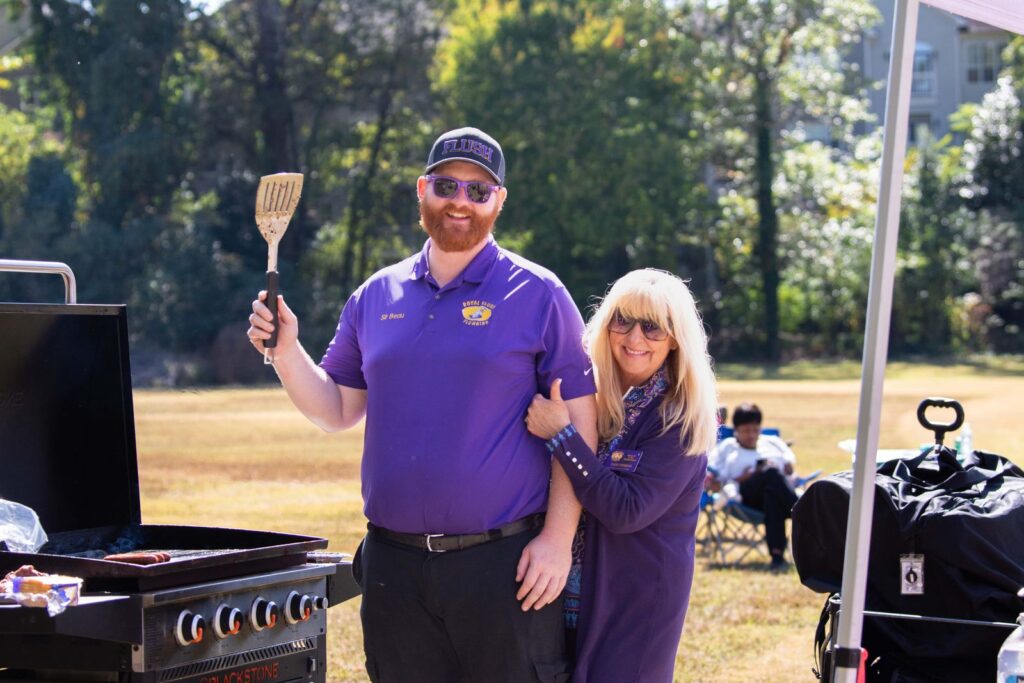 A joyful couple grilling at an outdoor BBQ event, enjoying a sunny afternoon.
