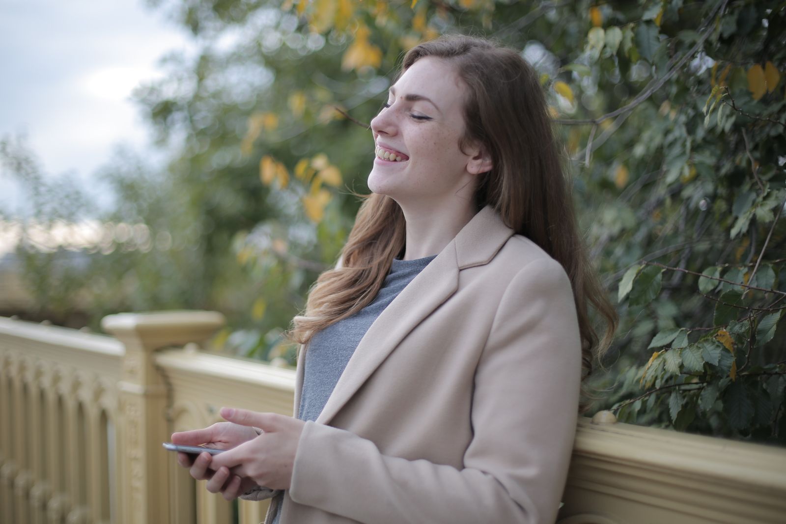 Smiling woman enjoying a moment of happiness outdoors during fall season.