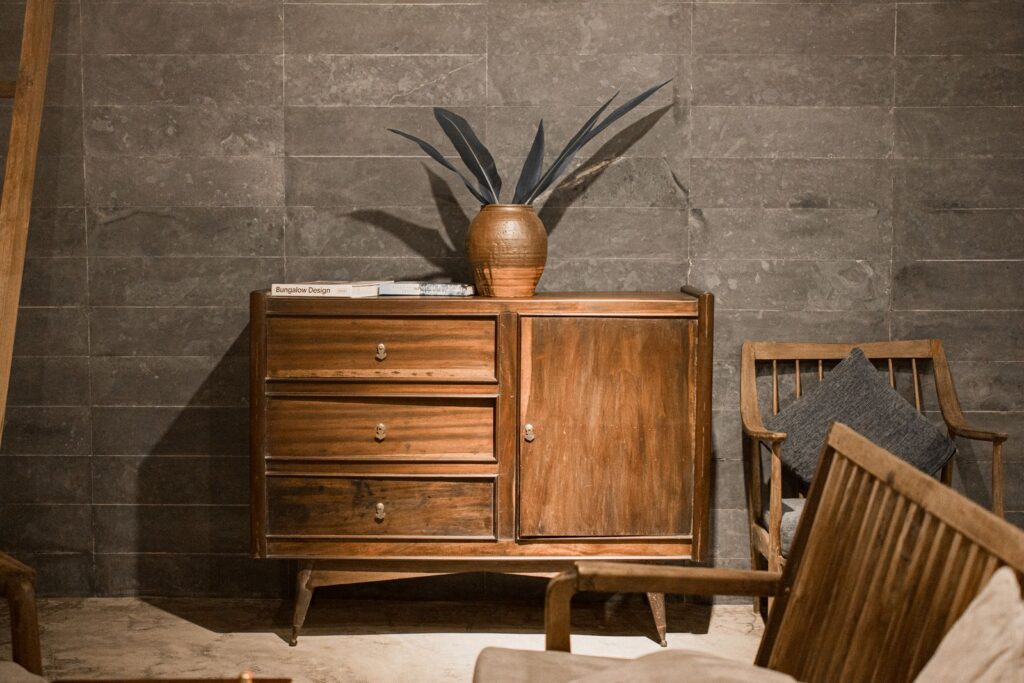 Elegant wooden cabinet against a stone wall, embodying rustic and minimalist decor in Hue, Vietnam.