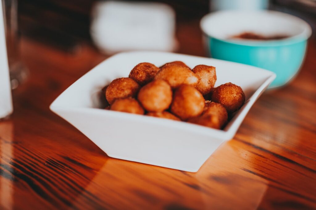 High angle of square ceramic bowl with yummy fried sweet snacks served on wooden table in kitchen