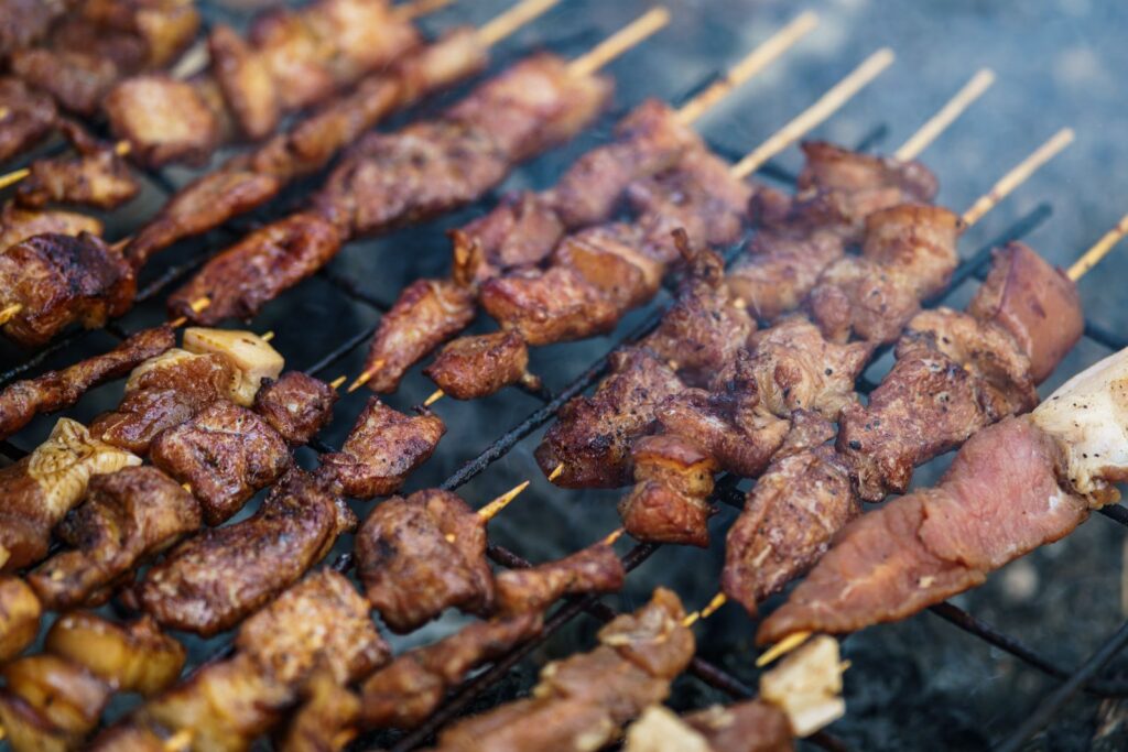 Delicious assortment of grilled meat skewers sizzling on an outdoor barbecue grill.