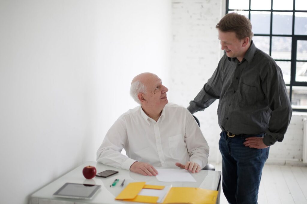 Positive men in different ages discussing project while working in loft styled workplace and looking at each other