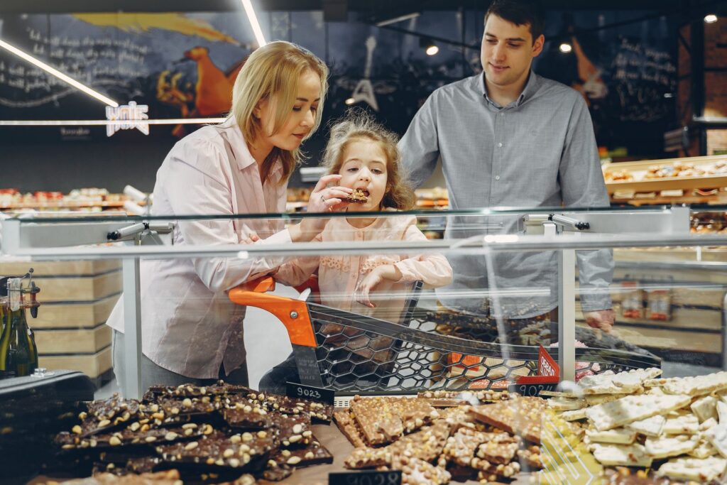 A family samples chocolates in a supermarket, sharing joy and togetherness.