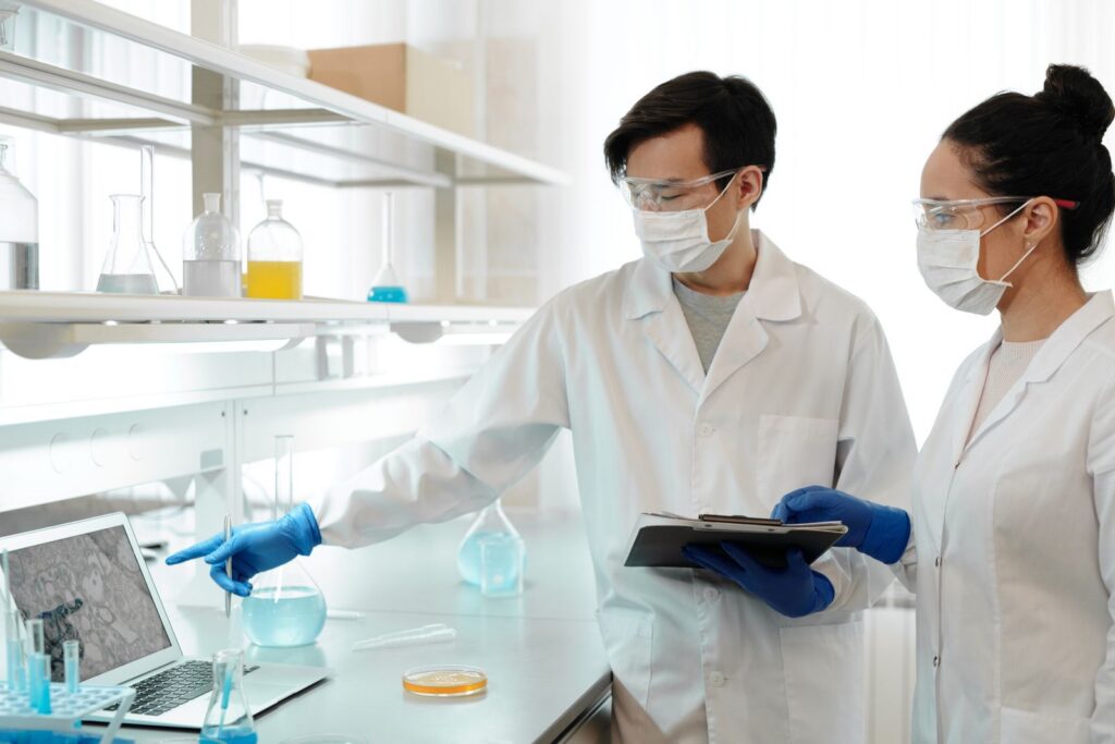 Two scientists in lab coats examining data on a computer in a research laboratory.