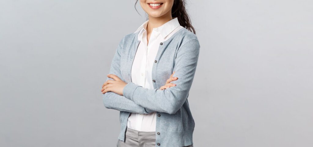 Confident woman in a casual outfit smiling with arms crossed, exuding professionalism.