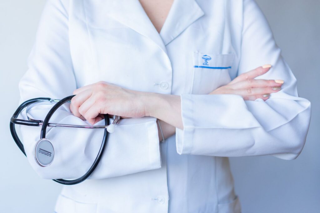 A close-up image of a doctor in a white coat with a stethoscope and arms crossed.