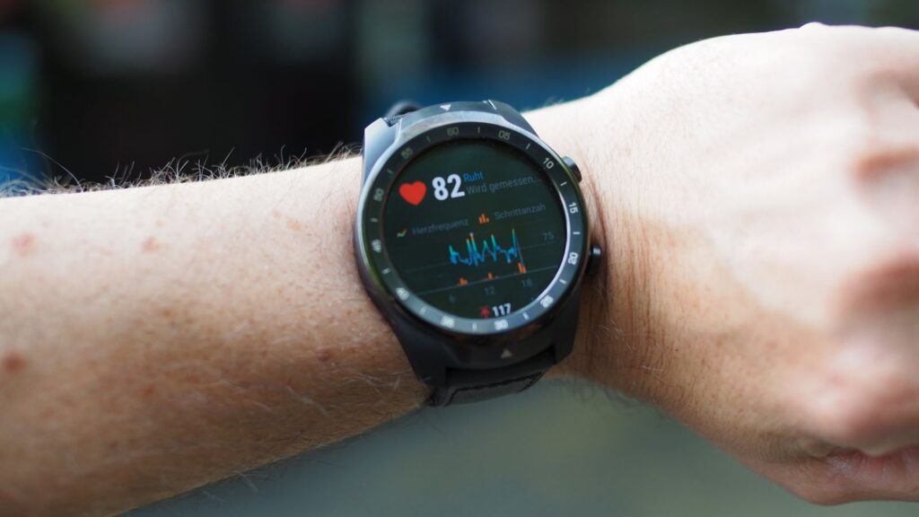 Close-up of a smartwatch showing heart rate and data on a person's wrist outdoors.
