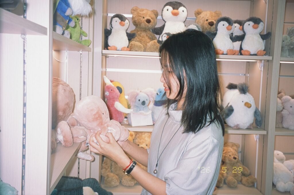 Young woman holding a pink stuffed toy in a shop.