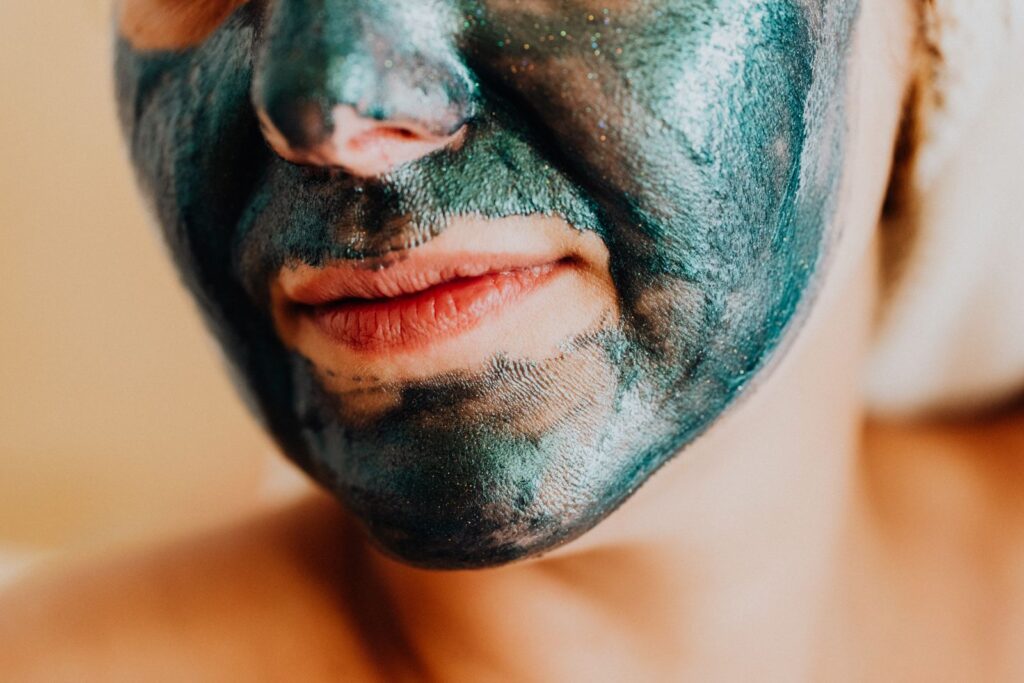 A close-up shot of a woman's face with a shimmering green facial mask for skincare.