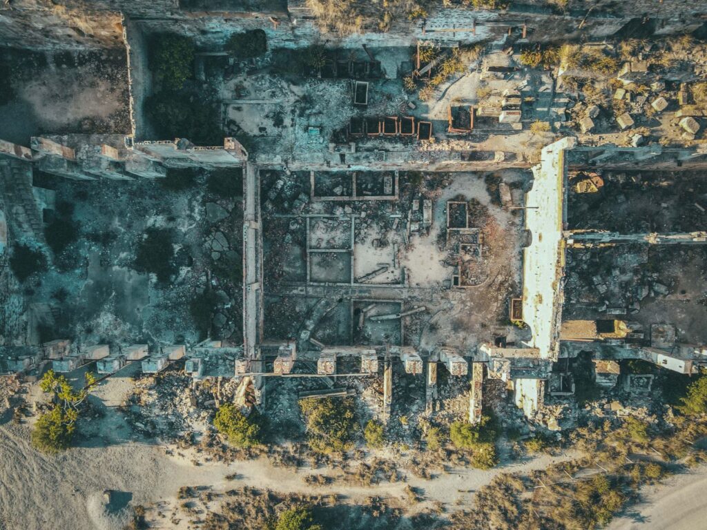 Drone view of ruined stone buildings with damaged walls and roofs located in uninhabited district