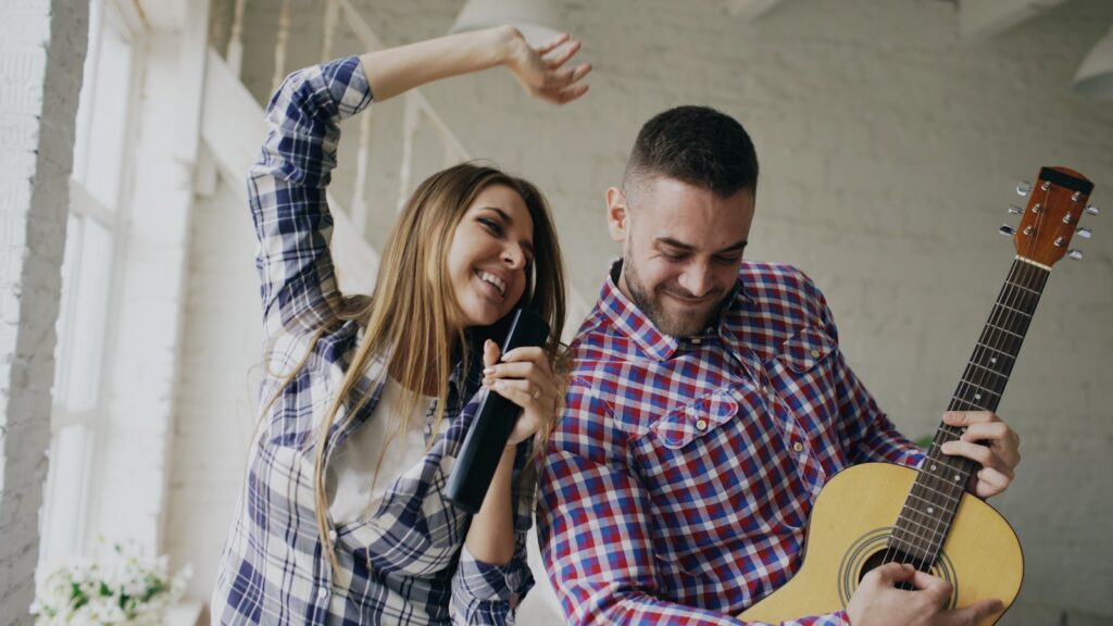 Couple singing and playing guitar together at home