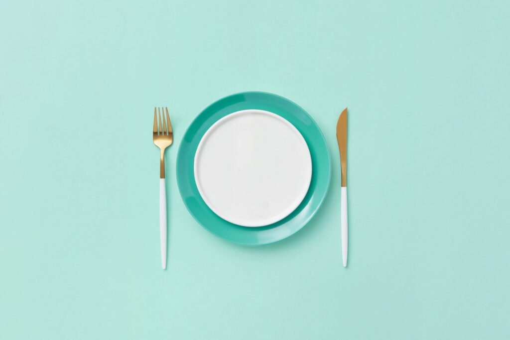 Teal plate set with fork and knife on a matching background. Minimalist and modern design.