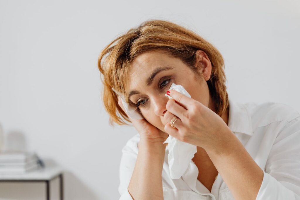Portrait of woman holding tissue, expressing emotion, wiping tears.