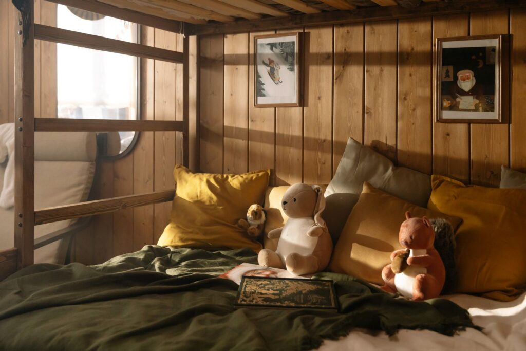 Charming rustic bedroom with plush toys, cozy bedding, and Christmas-themed decor. Warm and inviting atmosphere.