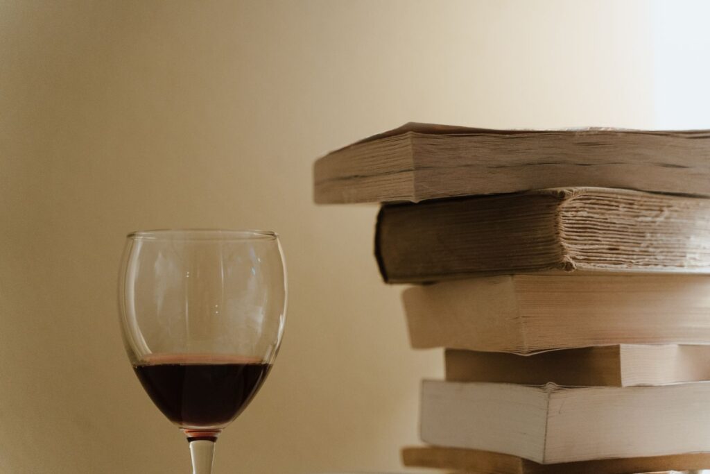 A serene still life photo featuring a stack of books and a glass of red wine, perfect for cozy reading vibes.