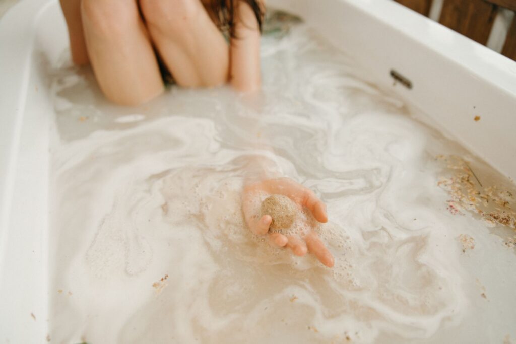 A serene moment in a bathtub as a person holds a dissolving bath bomb.