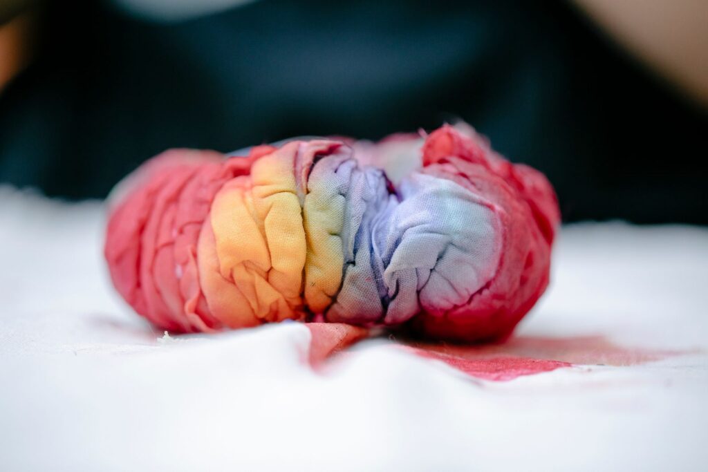 A detailed close-up of vibrant tie-dye fabric showcasing rainbow colors and creased texture.