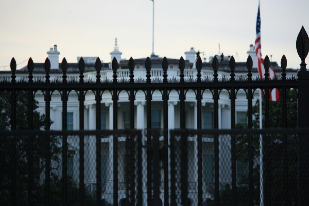 The white house behind a dark metal fence.