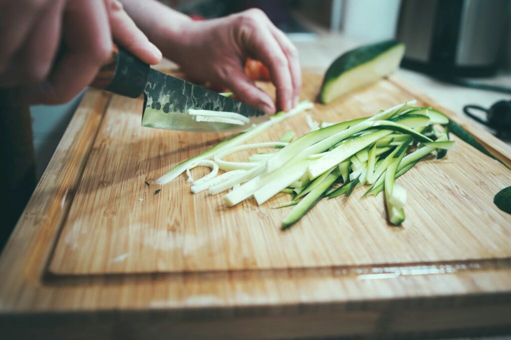 person slicing cucumber on cutting board with juice groove