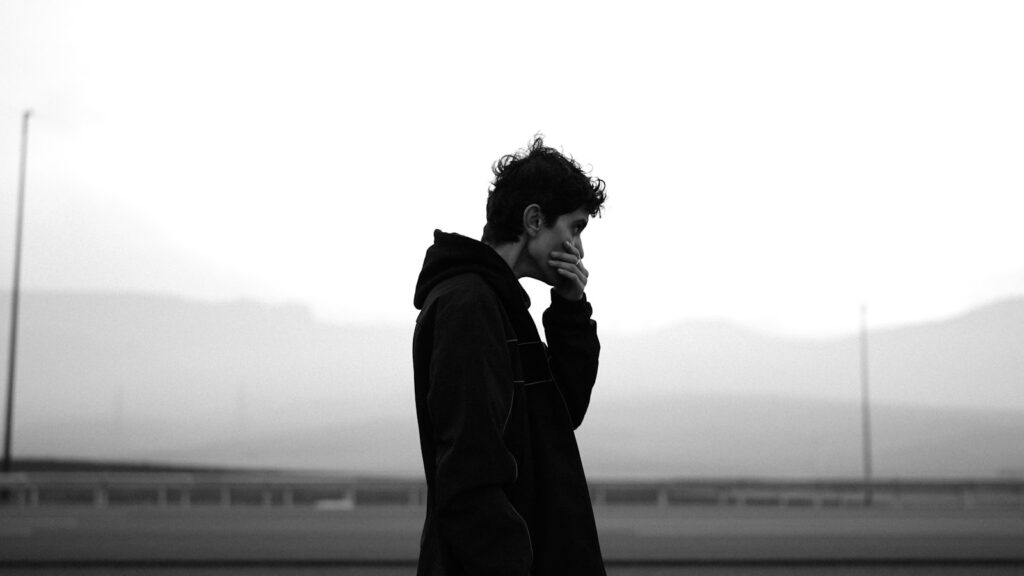 Man in hoodie talking on phone outdoors