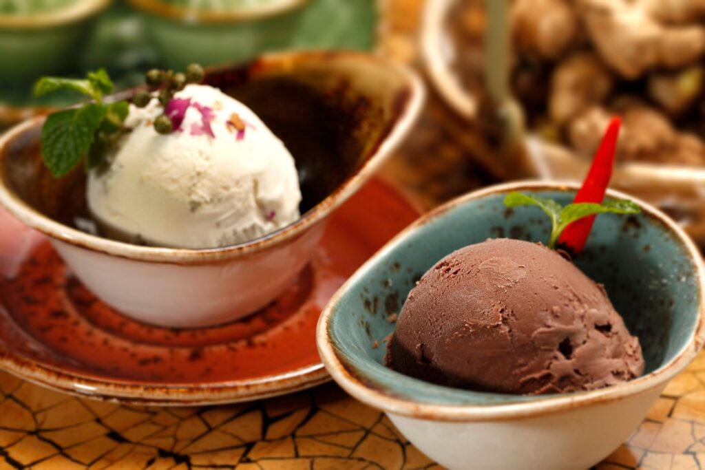 Close-up view of gourmet chocolate and vanilla ice cream served in decorative bowls with garnishes.