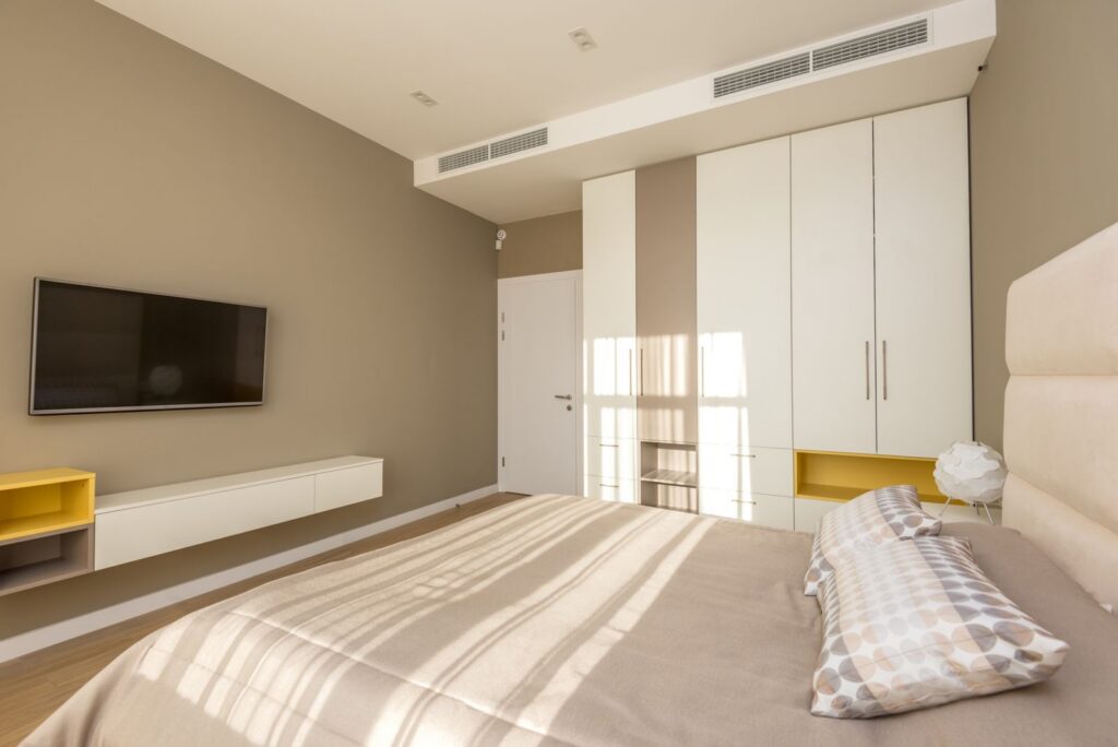 Bright and spacious modern bedroom with neutral tones and elegant decor.