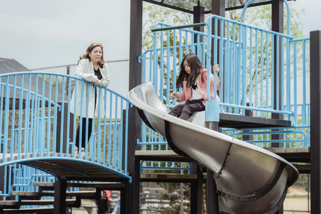 Mother and daughter having fun at a playground with a slide.