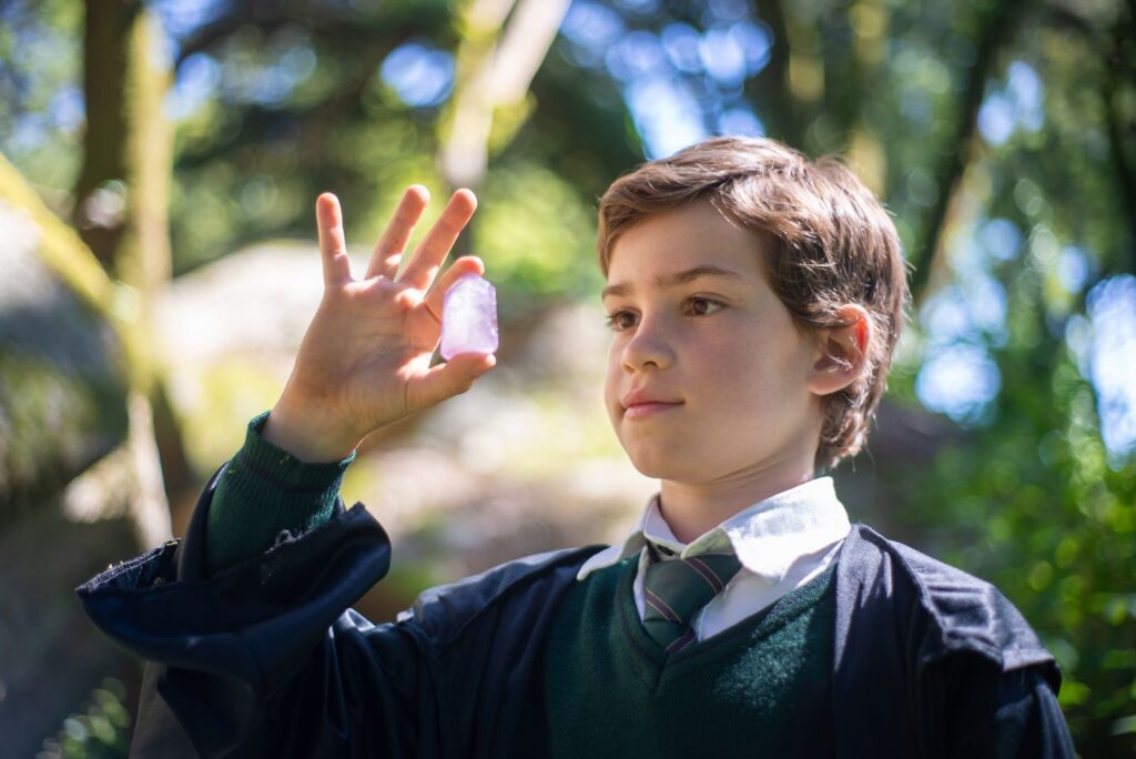 A young boy in a wizard costume holding a purple gemstone outdoors in Portugal.