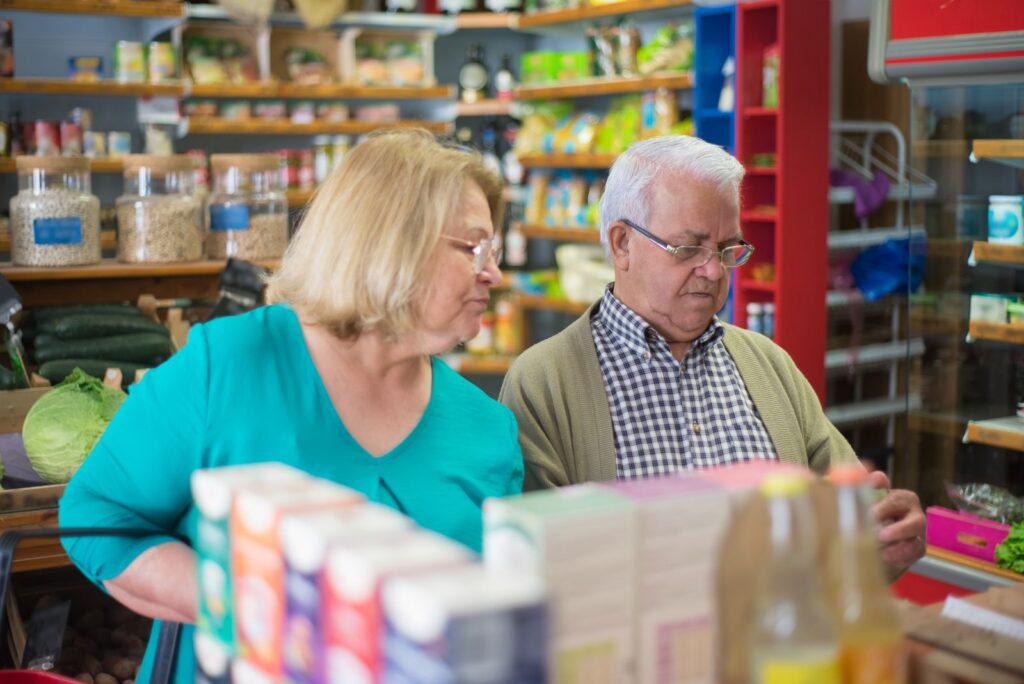 Elderly couple shopping in a cozy grocery store, enjoying a relaxed shopping experience.