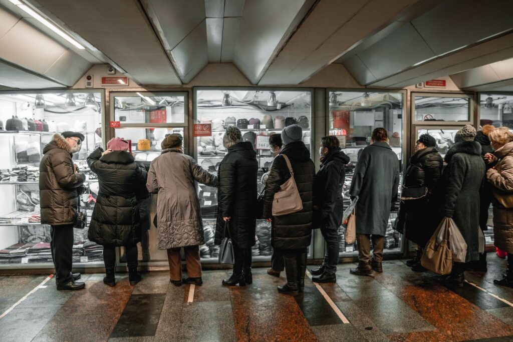 Adults browsing winter clothing in an indoor shopping mall during the day.