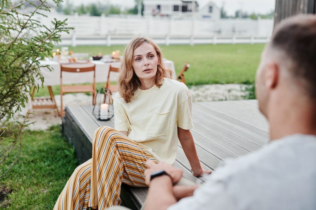 A couple engaged in a thoughtful conversation outdoors in a relaxed garden setting.