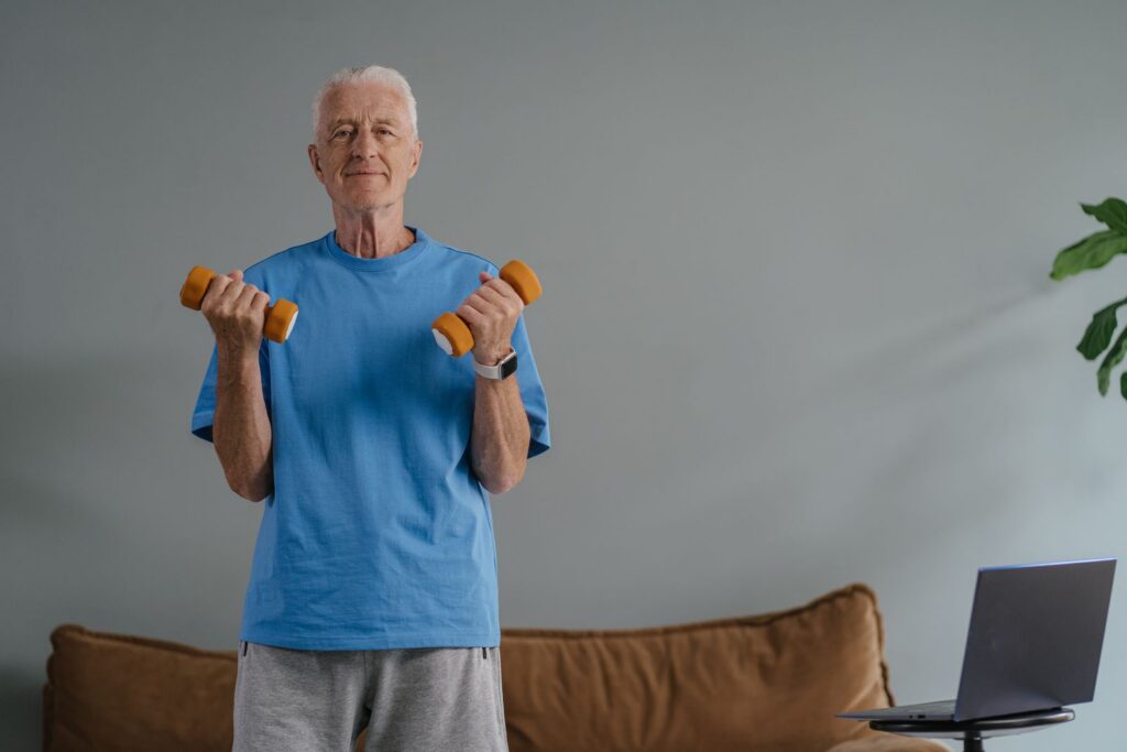 Elderly man lifting dumbbells indoors, promoting a healthy lifestyle.