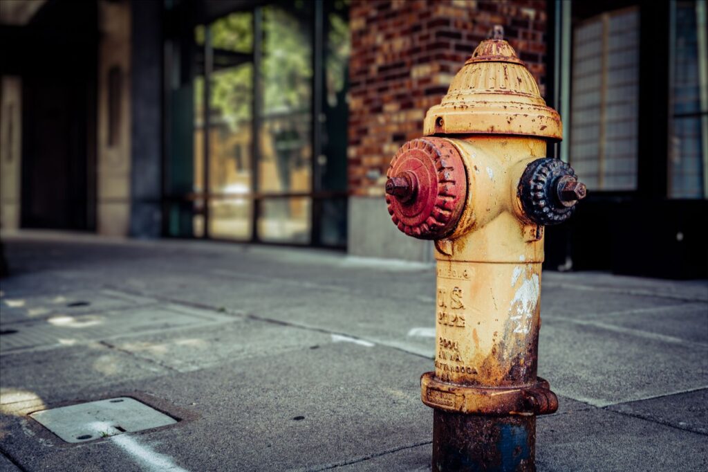 Close-up of an old, rusty fire hydrant on a city sidewalk capturing urban decay and vintage charm.