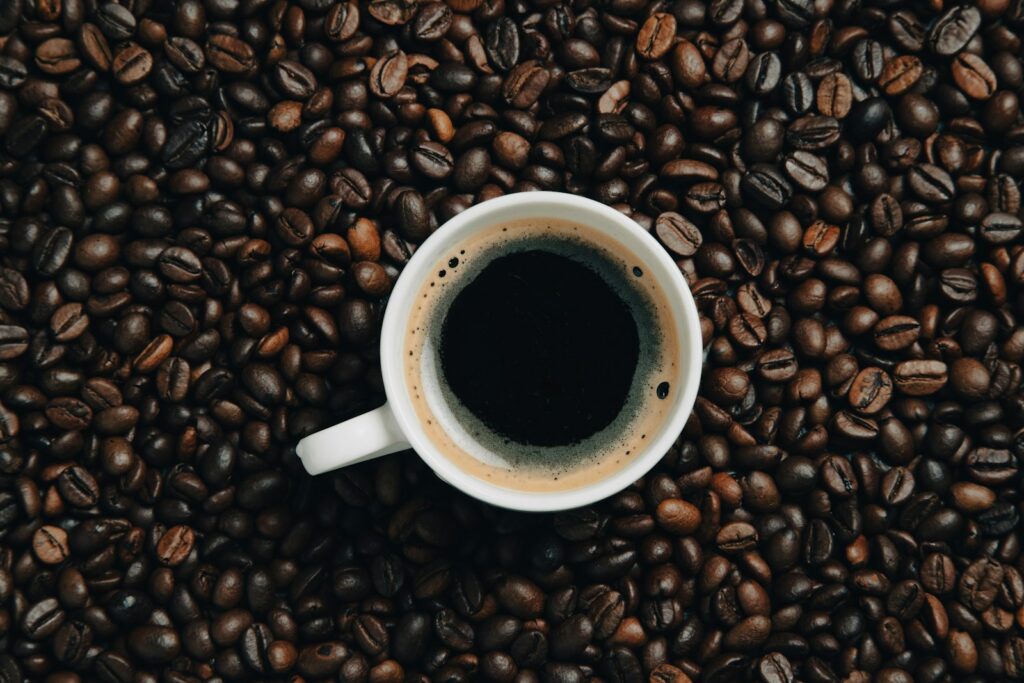 a cup of coffee sitting on top of a pile of coffee beans