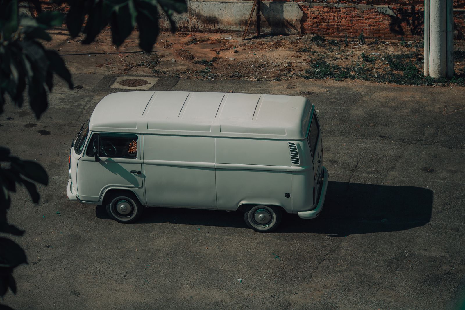 A classic white van parked on a street, surrounded by urban elements, captured in natural light.