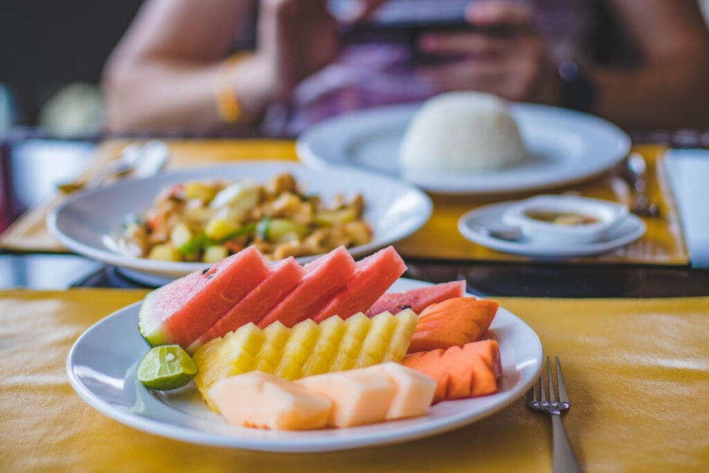 Vibrant and appetizing fruit platter served with a traditional Asian meal on a well-set dining table.