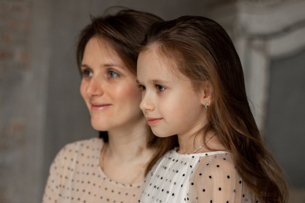 A warm portrait capturing the bond between a mother and daughter, both smiling softly.