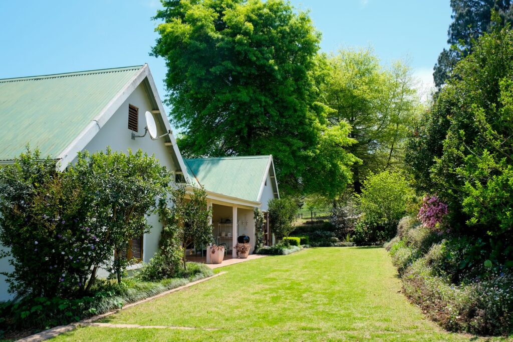 Beautiful cottage with lush green garden under a vibrant blue sky.