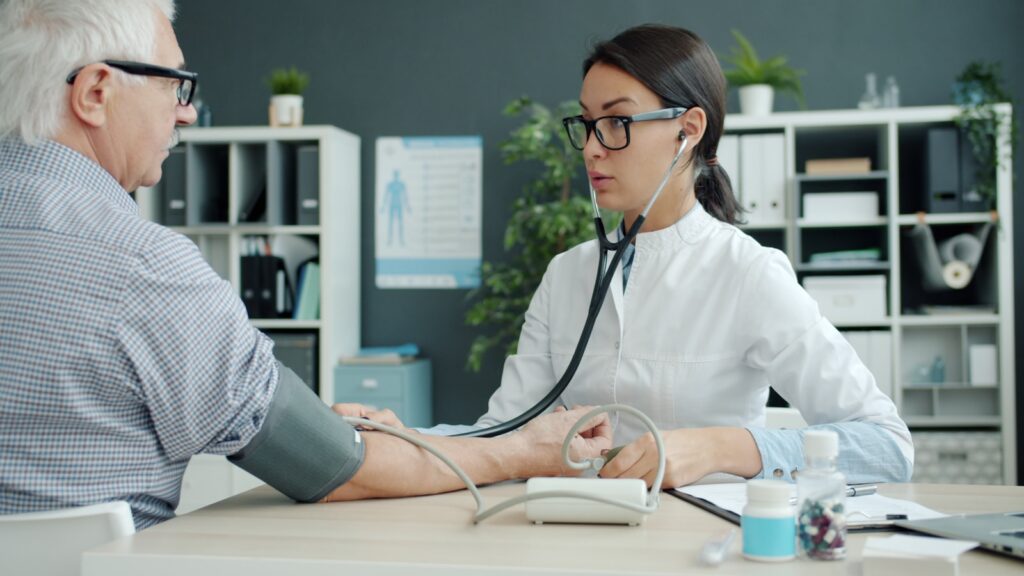Doctor takes elderly patient's blood pressure.