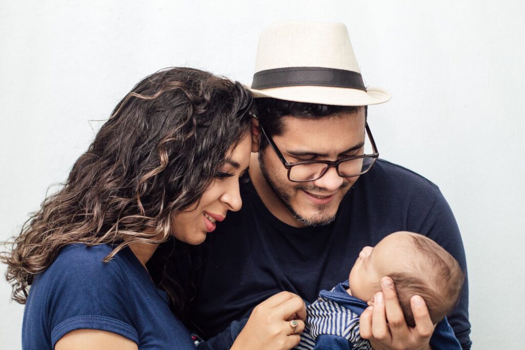 A loving couple shares a tender moment with their newborn child, showcasing family affection.