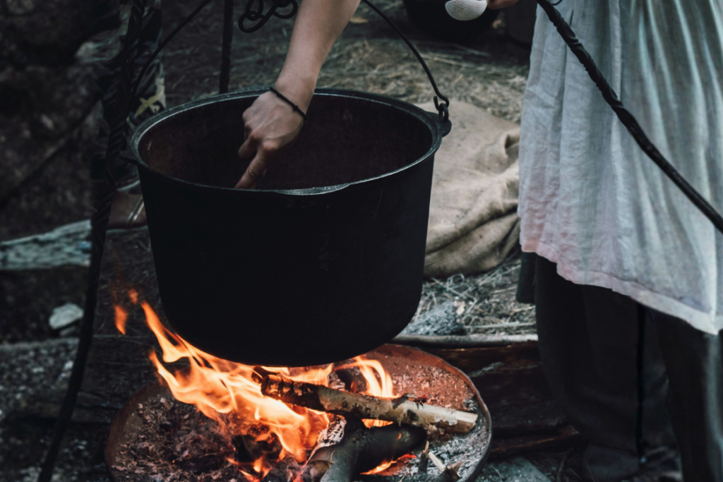 woman cooking on black metal cooking pot over fire