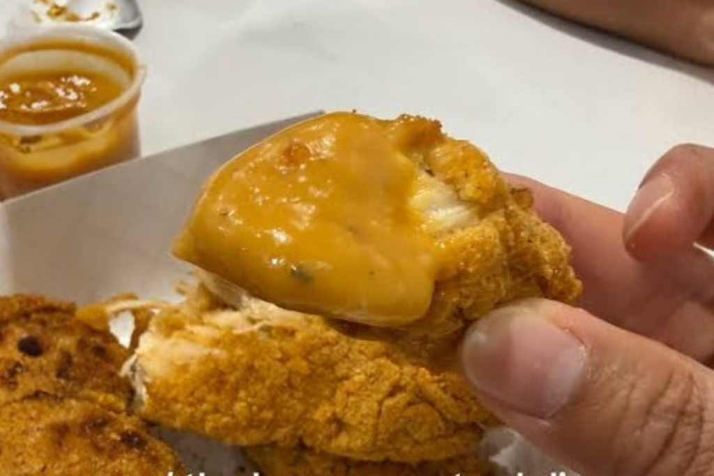 Costco chicken strip dipped in honey mustard sauce for full flavor