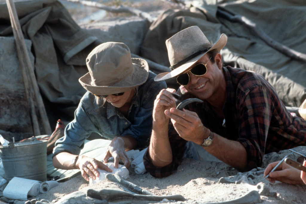 Dr. Alan Grant examines a dinosaur fossil at a paleontology dig site.
